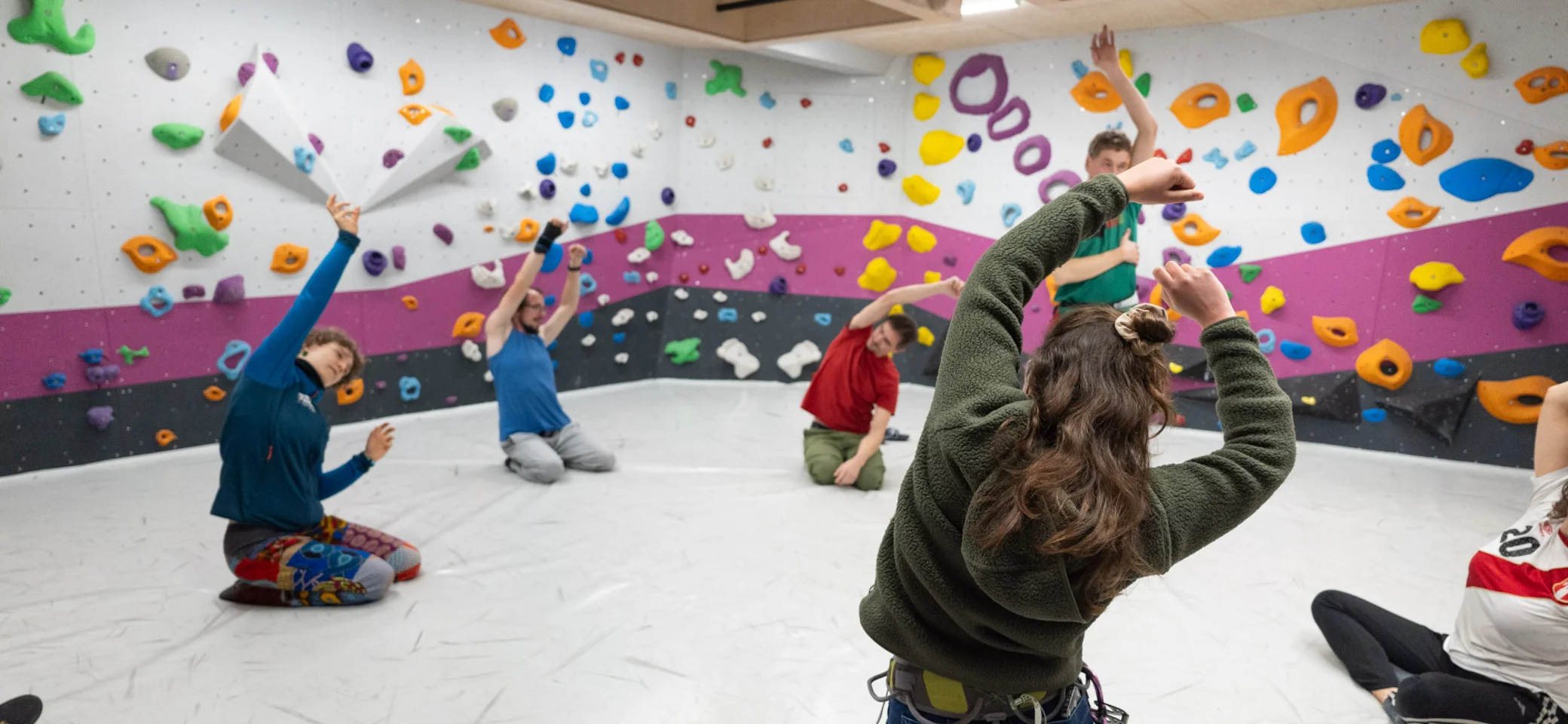 Ein Gruppe kletternder Personen wärmt sich im Boulderraum auf | © Maja Rohde