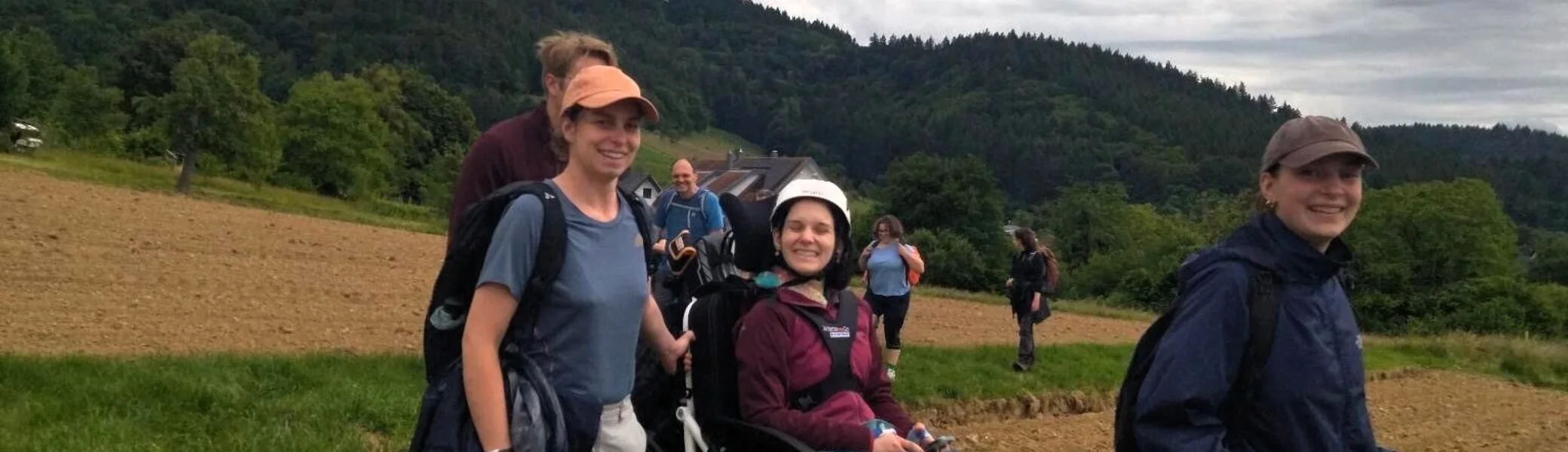 Eie Gruppe Menschen wandern über ein Feld, darunter eine Person in einem Wanderrolltuhl | © DAV/Freiburg-Breisgau/Josephine Kerzel/Wanderungen