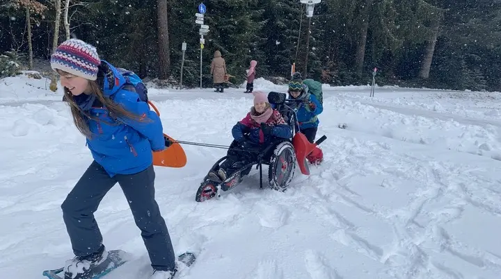 Eine Gruppe Jugendlicher unternehmen eine Winterwanderung mit Schneeschuhen und Wanderrollstuhl. | © DAV/Freiburg-Breisgau