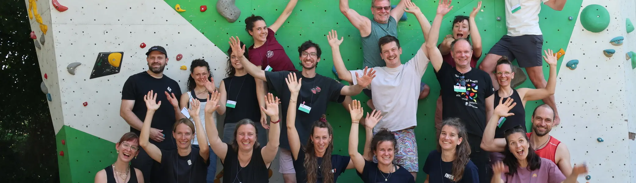 Die Teilnehmerinnen und Teilnehmer des Netzwerktreffens von "Seilschafft Inklusion!" stehen vor einer Kletterwand im Außenbereich der DAV Sektion Freiburg-Breisgau und strecken gut gelaunt die Hände in die Höhe | © Allpinistas + IWDR
