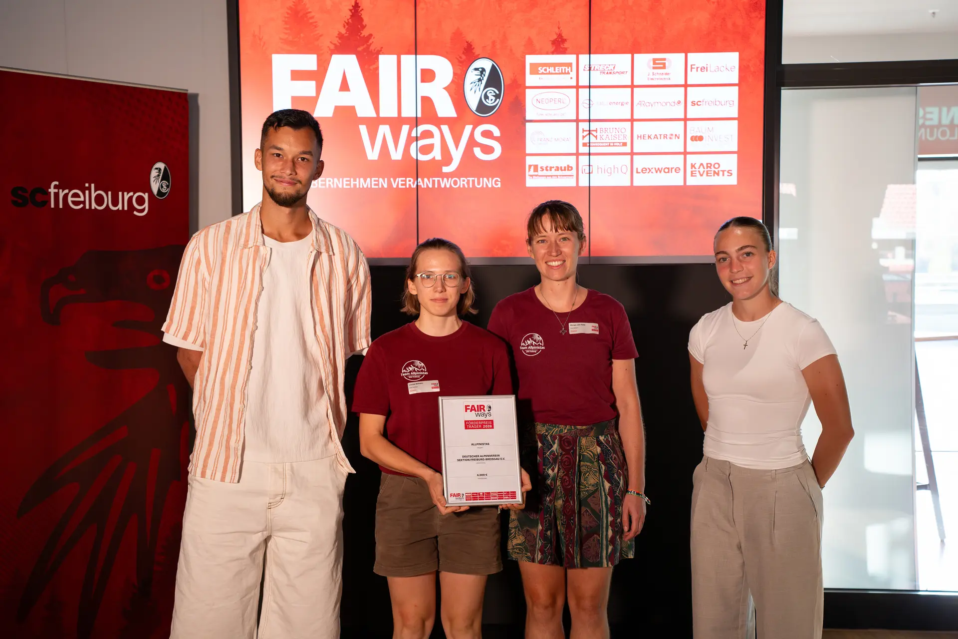 Stellvertretend für die Projektgruppe "Bunte Gipfel" nehmen die Allpinistas Miriam und Louisa (in der Mitte des Bildes) den FAIRways Förderpreis 2026 entgegen. Mit dabei: Mio Backhaus (rechts), Bundesliga-Team Männer des SC Freiburg, und Nora Scherer (links), Bundesliga-Team Frauen SC Freiburg | © SC Freiburg